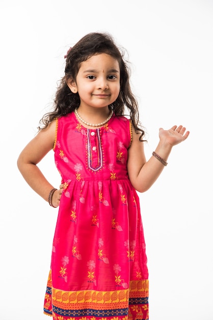 Porträt des netten kleinen indischen Mädchenmodells, das lokalisiert über weißem Hintergrund sitzt
