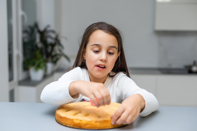 Porträt des netten kleinen Mädchens, das selbst gemachte Torte hält