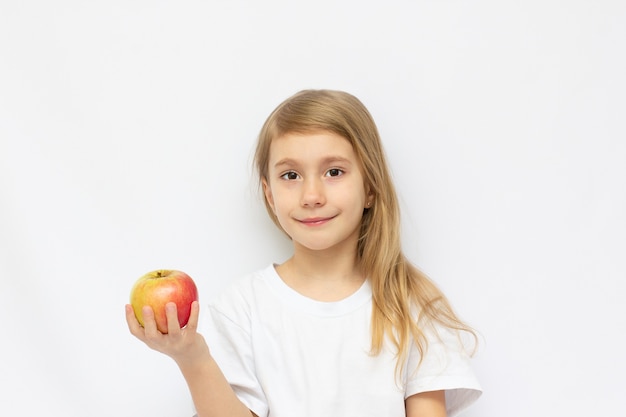 Porträt des niedlichen kleinen Mädchens, das einen Apfel hält - lokalisiert auf Weiß.