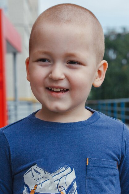 Porträt des niedlichen lächelnden kleinen Jungen im blauen Hemd, Außenaufnahme
