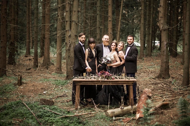Porträt des Paares und der Zeugen am Picknicktisch im Wald