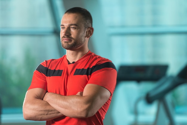 Porträt des Personal Trainers im Sportoutfit im Fitness-Center-Fitnessstudio, das stark steht