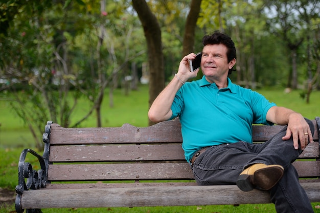 Porträt des reifen gutaussehenden Mannes, der am Park am Park spricht