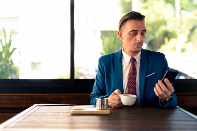 Porträt des reifen hübschen italienischen Geschäftsmannes, der am Kaffeehaus entspannt