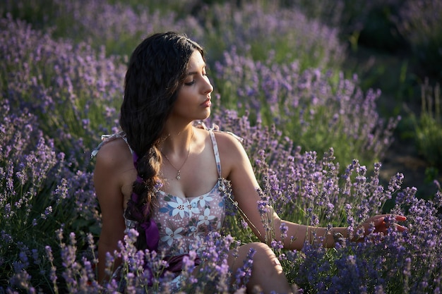 Porträt des reizenden Brunettemädchens auf dem Lavendelgebiet. Sommer-Lavendel-Modell posiert vor der Kamera.