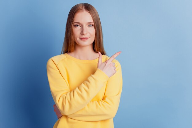 Porträt des reizenden Promotermädchens zeigt Fingerleerstelle auf blauem Hintergrund an