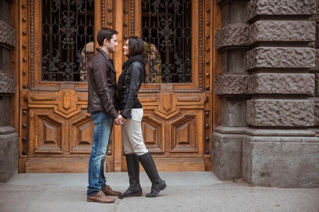 Porträt des romantischen Paares, das draußen mit alter Holztür auf bacground steht