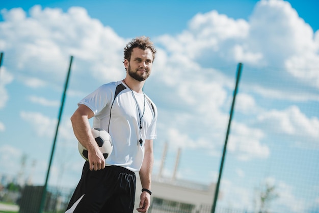 Porträt des Schiedsrichters, der den Fußball hält, während er auf dem Fußballplatz steht