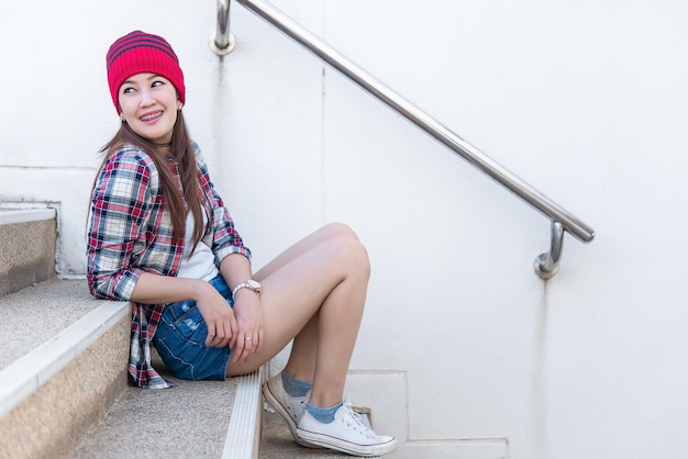 Porträt des schönen asiatischen Hipster-Mädchens auf TreppenhintergrundLifestyle der modernen FrauThailand glückliche Frau macht ein Fotokonzept