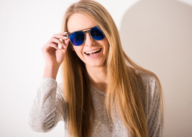 Porträt des schönen blonden Mädchens mit Sonnenbrille lächelt