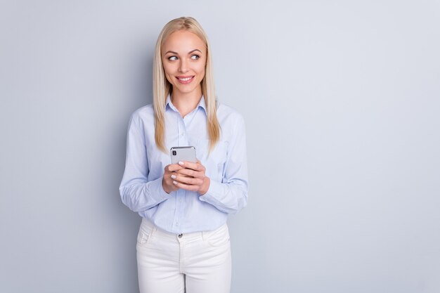 Porträt des schönen charmanten Mädchens verwenden Smartphone-Look Copyspace auf grauer Wand