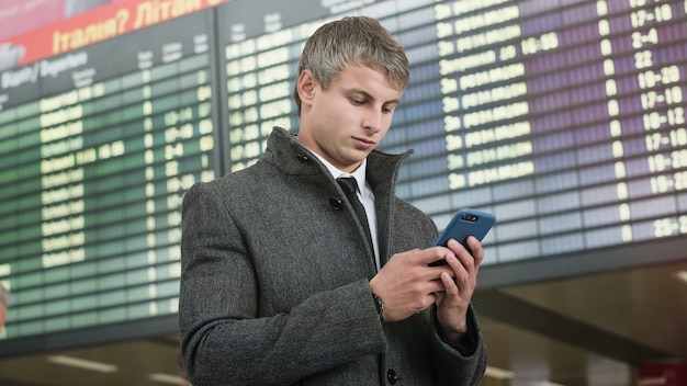 Porträt des schönen Geschäftsmannes unter Verwendung des Smartphones.