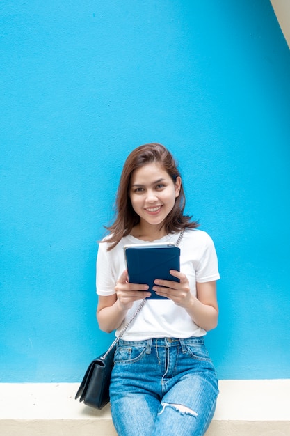 Porträt des schönen Hochschulstudenten lächelt auf blauem Wandhintergrund