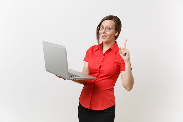 Porträt des schönen jungen Geschäftslehrer-Frauenbenutzers im roten Hemd, Gläser, die das Schreiben auf dem Laptop-PC-Computer lokalisiert auf weißem Hintergrund arbeiten. Bildung oder Lehre im Hochschulkonzept