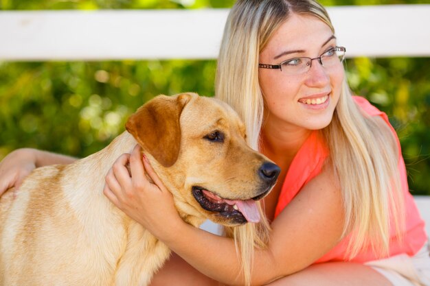 Porträt des schönen jungen Mädchens mit ihrem Hund Labrador Retriever im Freien im schönen Sommerpark