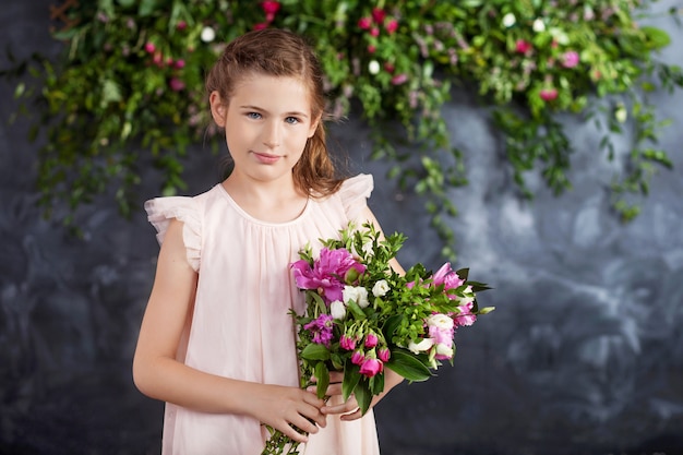Porträt des schönen kleinen Mädchens mit einem Blumenstrauß.