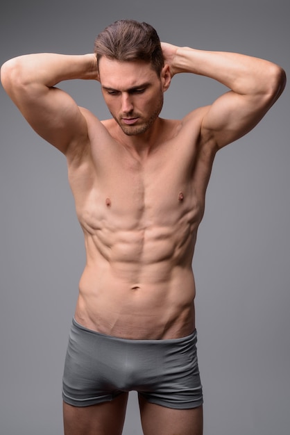 Porträt des schönen muskulösen hemdlosen Mannes auf grau