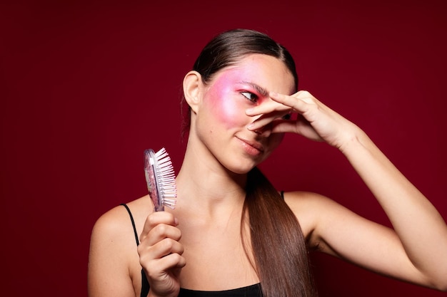 Porträt des schönen rosa Gesichtsmake-ups der jungen Frau, das attraktiven Blick mit einer unveränderten Kammnahaufnahme aufwirft