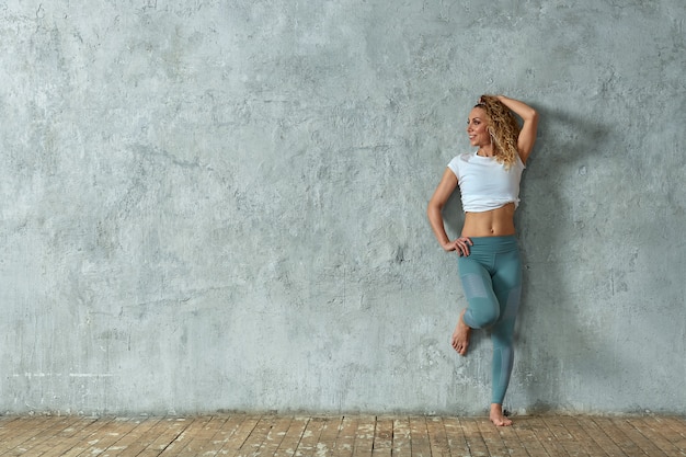 Porträt des schönen sexy blonden lächelnden Mädchens, auf grauem Hintergrund