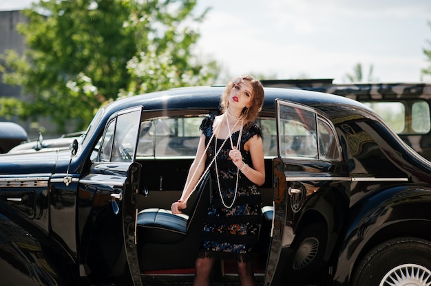 Foto porträt des schönen sexy gelockten modemädchenmodells mit hellem make-up im retrostil nahe weinleseauto