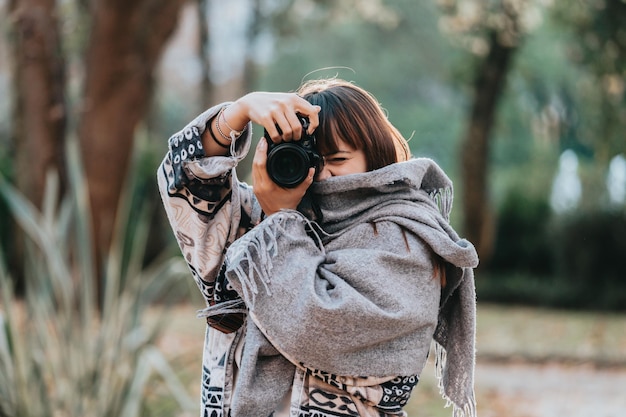 Porträt des schönen spanischen Frauenfotografen mit Digitalkamera. hält professionelle Kamera. erstaunliche rote haare posieren im freien mit kamera, rothaarige frau entspannt sich im park. Lächeln Kamera