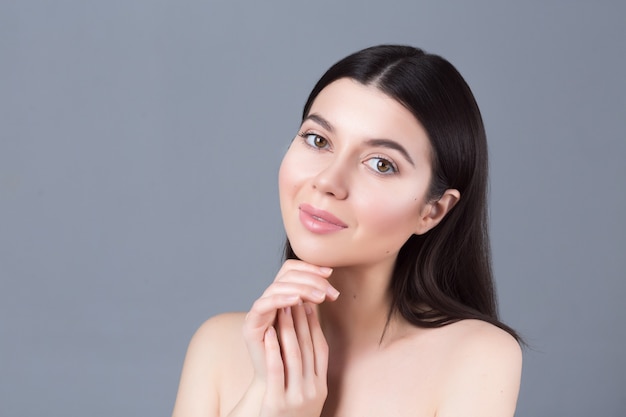 Porträt des Schönheitsmädchens mit natürlichem nacktem Make-up, das ihr Gesicht berührt. Wellness, Hautpflege