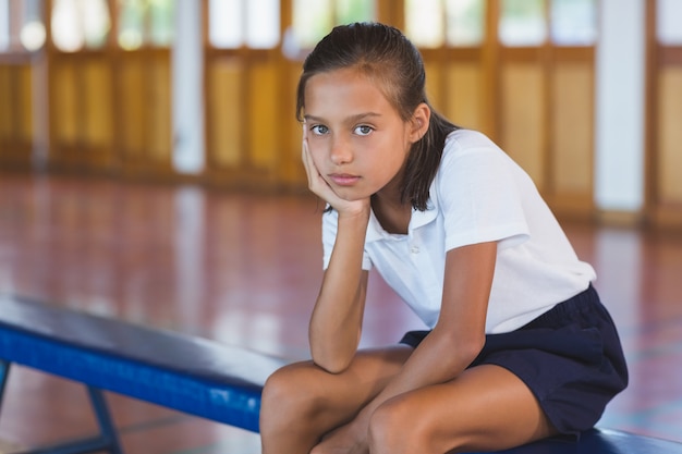 Porträt des Schulmädchens, das im Basketballplatz sitzt