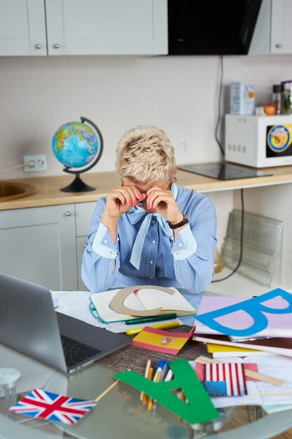 Porträt des selbstbewussten gut aussehenden Lehrers, der am Tisch sitzt