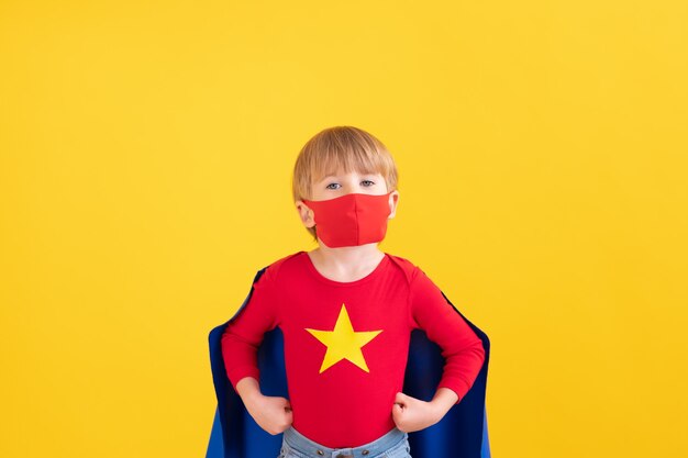 Porträt des Superheldenkindes gegen gelbe Papierwand.