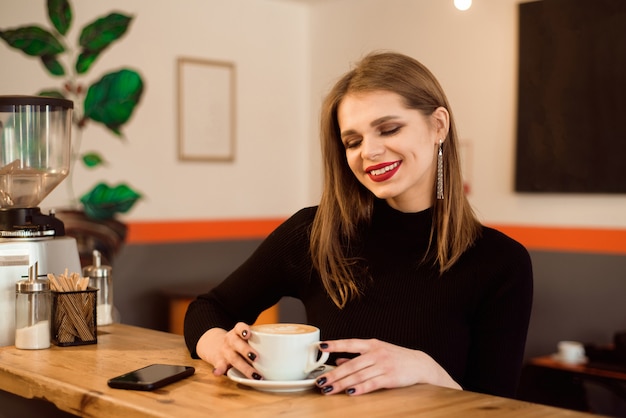 Porträt des trinkenden Kaffees der jungen Frau im Café.