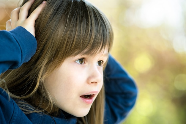 Porträt des überraschten Kindermädchens, das Hände an ihrem Kopf draußen im Sommer hält.