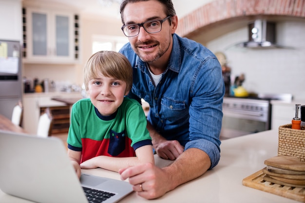 Porträt des Vaters und des Sohns, die Laptop in der Küche verwenden