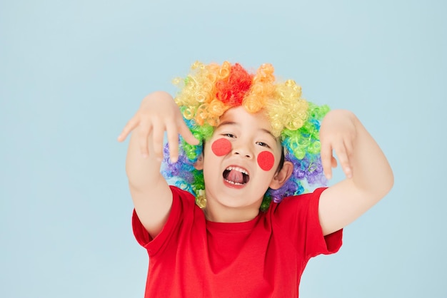 Porträt des verspielten Clowns des kleinen Jungen in roter Perücke