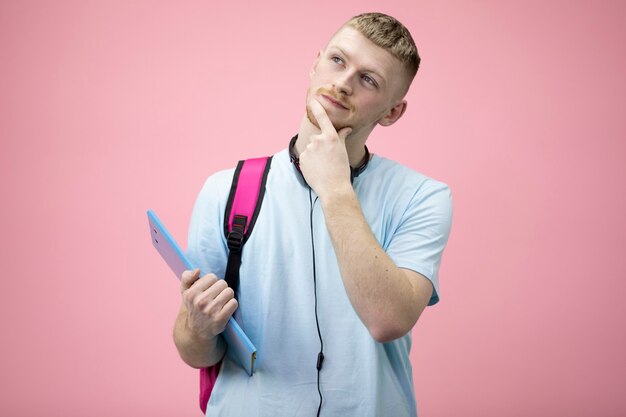 Porträt des verträumten oder nachdenklichen Schülers im T-Shirt mit Notizblock auf Händen.