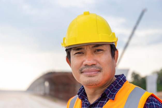 Porträt des Vorarbeiters in Hardhat auf der Infrastrukturbaustelle Bauingenieur, der das Projekt auf der Baustelle überprüft