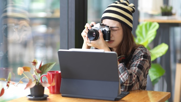 Porträt des weiblichen Teenagers, der Foto mit Digitalkamera beim entspannten Sitzen im Café nimmt