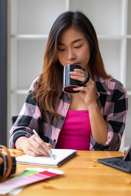 Porträt des weiblichen Teenagers, der Kaffee während des Online-Studierens im Wohnzimmer trinkt