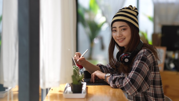 Porträt des weiblichen Teenagers lächelnd und in die Kamera schauend beim Entspannen mit Kopfhörer und Tablet