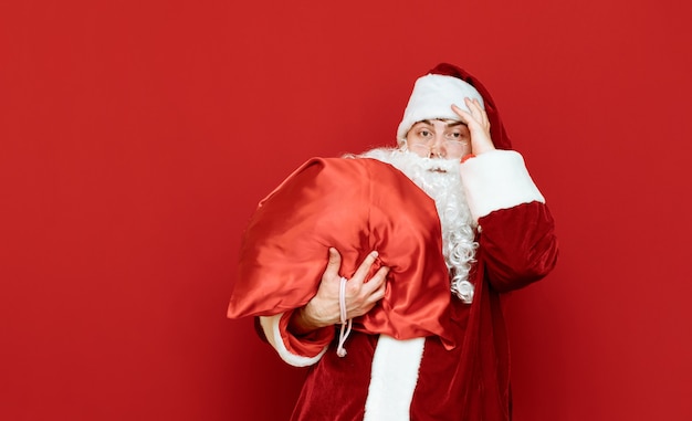 Porträt des Weihnachtsmannes mit schwerer Tasche mit Geschenken