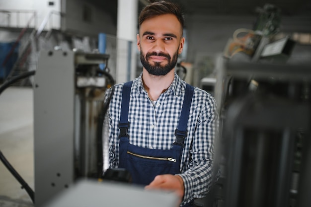 Porträt des Wirtschaftsingenieurs Fabrikarbeiter mit Schutzhelm, der in der Fabrik steht