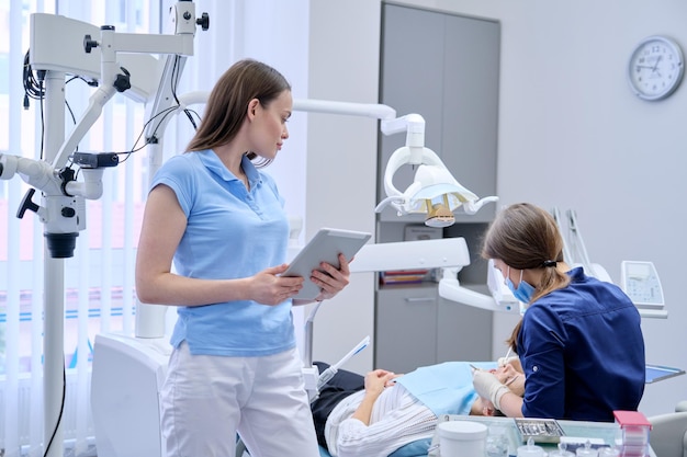 Porträt des Zahnarztdoktors mit digitaler Tablette, weibliches Arbeiten mit Computer. Zahnmedizin im Gesundheitswesen, Zahnklinik, Patientenbesuch und Untersuchung durch Zahnarzthintergrund