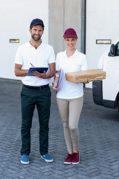 Foto porträt des zustellers und der frau, die mit klemmbrett und paket stehen