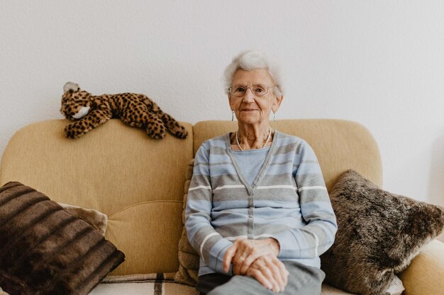 Foto porträt einer älteren frau, die zu hause auf dem sofa sitzt