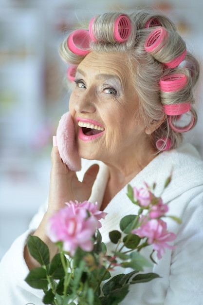 Porträt einer älteren Frau im Bademantel beim Auftragen von Make-up