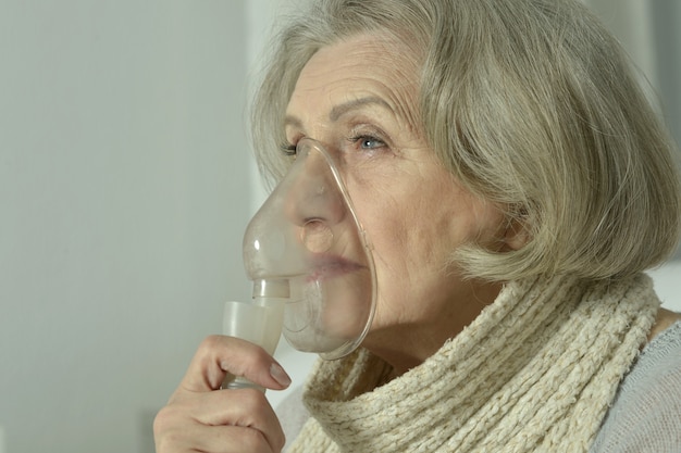 Porträt einer älteren Frau mit Grippeinhalation