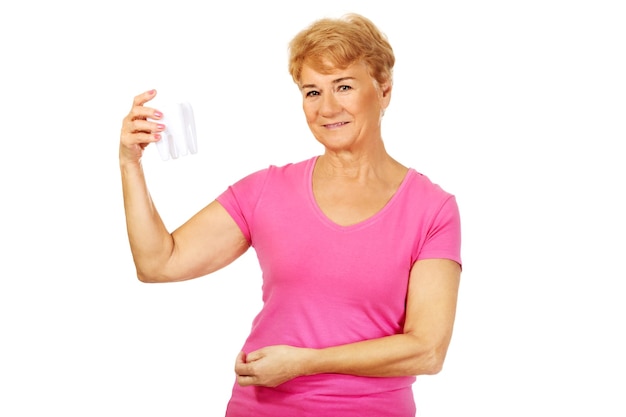 Porträt einer älteren Frau mit Zahnprothesen, die vor weißem Hintergrund steht