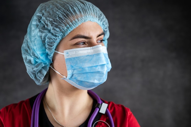 Porträt einer Ärztin in Uniform mit medizinischer Gesichtsmaske und medizinischen Handschuhen, Stethoskop. Medizinisches Konzept