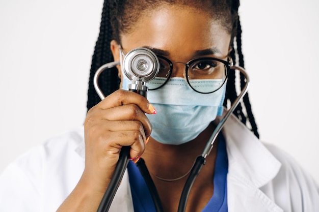Porträt einer afrikanischen Ärztin in Kittel und Laborkittel mit Stethoskop vor weißem Hintergrund