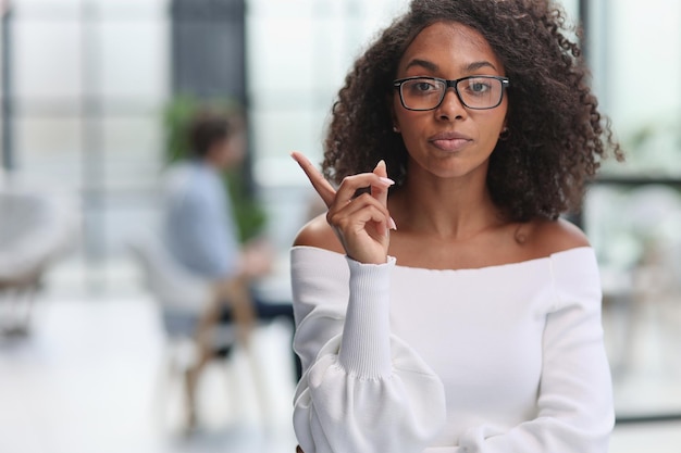 Porträt einer afroamerikanischen jungen Geschäftsfrau, die zur Seite eine Fingergeste zeigt