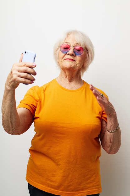 Porträt einer alten, freundlichen Frau, glücklicher Lebensstil in gelben T-Shirts, isolierter Hintergrund